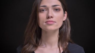 Yakın çekim portre Genç beyaz uzun saçlı esmer kız cidden içine kamera siyah arka plan üzerine poz.