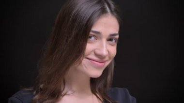 Yakın çekim portre Genç beyaz uzun saçlı esmer kız flirtingly içine kamera siyah arka plan üzerinde gülümseyen.