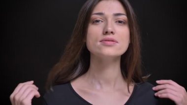 Yakın çekim portre Genç beyaz uzun saçlı esmer kız flirtingly kamera siyah arka plan üzerine göz kırpıyor.