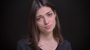Genç beyaz uzun saçlı esmer kız utanarak kamera siyah arka plan üzerine içine izlerken yakın çekim portre.