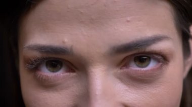 Yakın çekim göz-portresi Genç beyaz uzun saçlı esmer kız kamera siyah arka plan üzerine içine sakince izlerken.