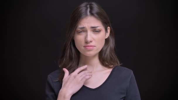 Portrait of young caucasian long-haired brunette girl having sore throat and coughing on black background. — Stock Video