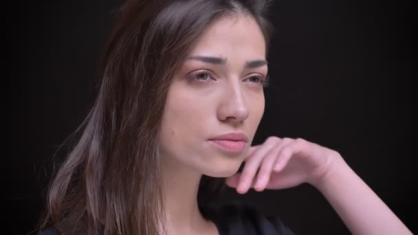 Close-up portrait of young caucasian long-haired brunette girl flirtingly posing into camera on black background. — Stock Video