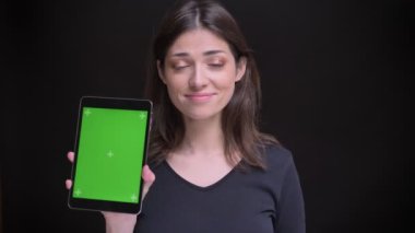 Tablet ve onun dik yeşil ekran kamera siyah arka plan üzerine içine gösterileri izlerken çok uzun saçlı esmer kız.
