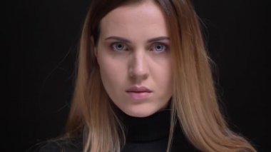 Yakın çekim portre Genç beyaz uzun saçlı sarışın kızın cidden içine kamera siyah arka plan üzerine izlerken.