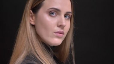 Genç beyaz uzun saçlı sarışın kız portresi yakın çekim için kamera döner ve ciddi siyah arka plan üzerine saatler.
