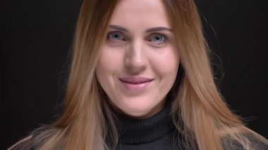 Yakın çekim portre Genç beyaz uzun saçlı sarışın kızın içine kamera siyah arka plan üzerine naçizane gülümseyen.