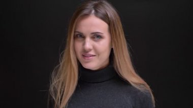 Genç beyaz uzun saçlı sarışın kız kamera siyah arka plan üzerine içine sakince gülümseyerek portresi.