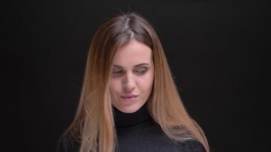 Genç beyaz uzun saçlı sarışın kız flirtingly içine kamera siyah arka plan üzerine izlerken portresi
