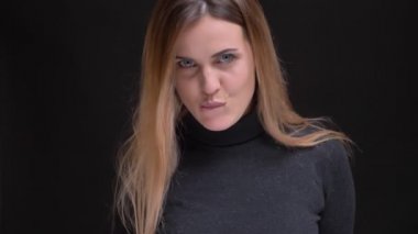 Flirtingly onun dudak ısırma ve siyah arka plan üzerine kamera içine izlerken genç beyaz uzun saçlı sarışın kız portresi.