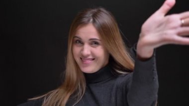 Sevinçle hareketli siyah arka plan üzerine beyaz uzun saçlı sarışın kız portresi.