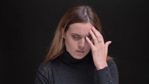 Retrato de una joven rubia caucásica de pelo largo con dolor de cabeza y masaje sobre fondo negro . — Vídeos de Stock