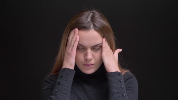 Porträtt av unga kaukasiska långhåriga blonda flicka lidande från huvudvärk och att göra massage på svart bakgrund. — Stockvideo