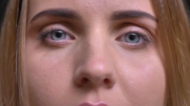 Yakın çekim göz-portresi Genç beyaz uzun saçlı sarışın kız kamera siyah arka plan üzerine içine sakince izlerken.