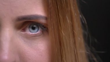 Yakın çekim yarı-portresi Genç beyaz uzun saçlı sarışın kız cidden içine kamera siyah arka plan üzerine izlerken.