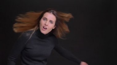 Sevinçle etrafında dönen ve siyah arka plan üzerine bir öpücük üfleme Genç beyaz uzun saçlı sarışın kız portresi.