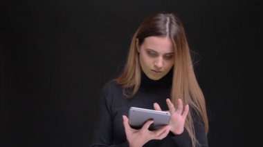 Dikkatle tablet izliyor ve onun yeşil perde içine kamera siyah arka plan üzerinde gösterilen genç uzun saçlı sarışın kız.