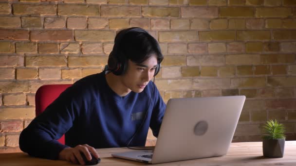 Retrato de close-up de jovem atraente estudante coreano masculino verificando no laptop e ficando animado por causa do sucesso — Vídeo de Stock