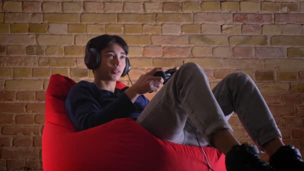 Portrait rapproché d'un jeune coréen jouant à des jeux vidéo en utilisant la console pour être heureux de gagner et de célébrer — Video