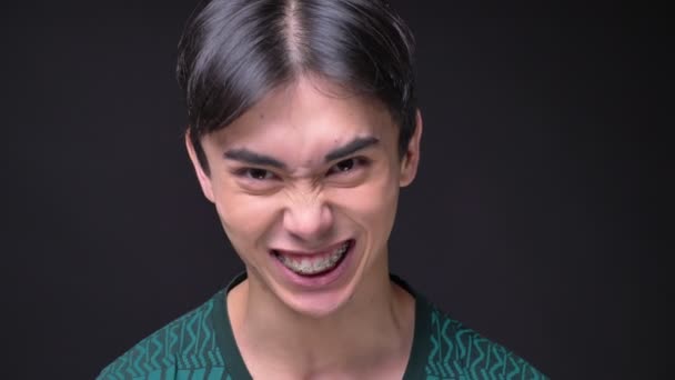 Närbild porträtt av ung bedårande koreanska manliga tittar kameran skrattar och busar runt — Stockvideo