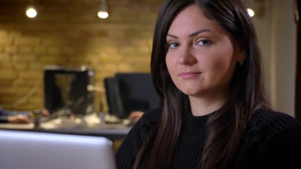 Portrét dospělých bruneta usmívající se kavkazské podnikatelka, zatímco sedí v přední části notebooku při pohledu na fotoaparát — Stock video