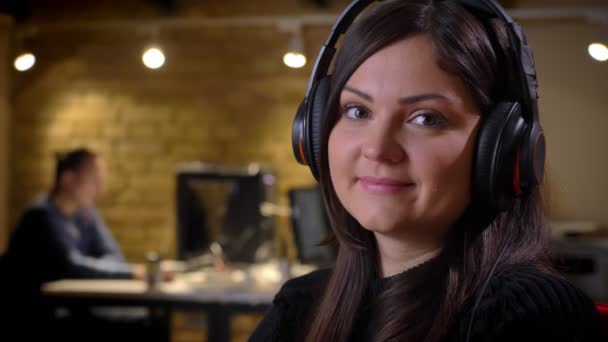 Vértes felnőtt kaukázusi boldog üzletasszony fejhallgató fényképezőgép ans mosolyogva a munkahelyen lét nézett — Stock videók
