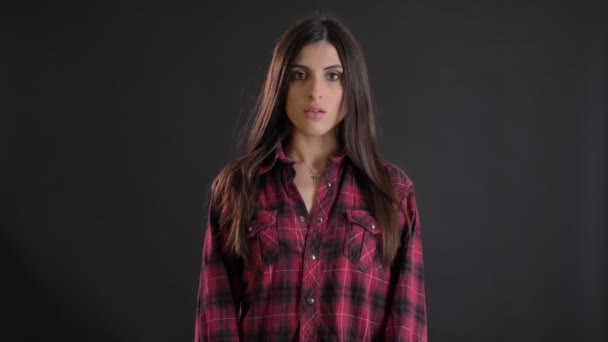 Retrato de caucásico de pelo largo morena chica mirando seriamente en la cámara sobre fondo negro . — Vídeo de stock