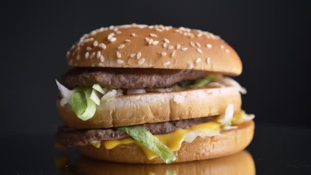 Close-up opnamen van smakelijk dubbele cheeseburger met twee sappige pasteitjes en de specerijen — Stockvideo