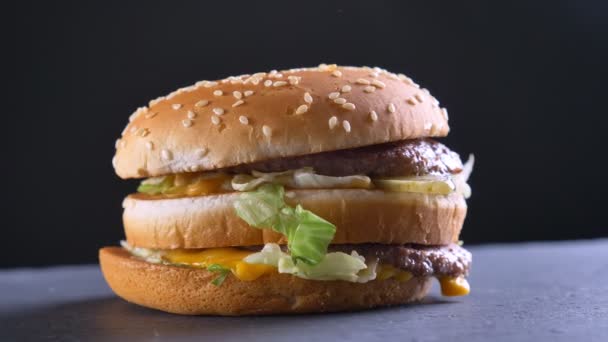 Closeup σουτ του ορεκτικές διπλό cheeseburger με δύο ζουμερά μπιφτέκια και τα καρυκεύματα — Αρχείο Βίντεο