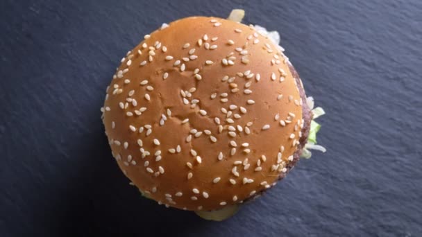 Сверху вниз съёмка аппетитного двойного чизбургера с кунжутом на булочках, вращающихся в движении — стоковое видео