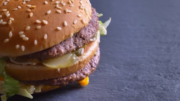 Tiro close-up de saboroso cheeseburger souble com dois rissóis e queijo girando em torno de em movimento — Vídeo de Stock