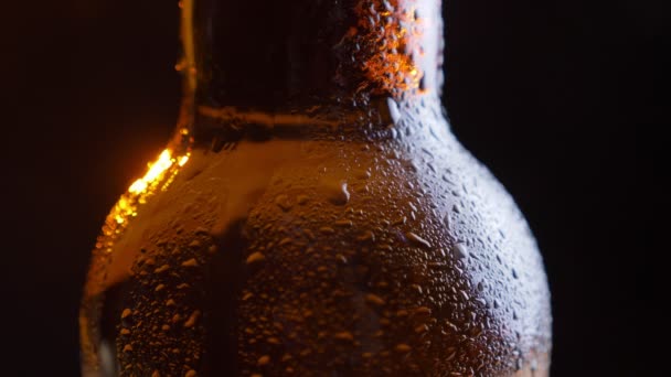 Closeup natáčení zářící ledové pivo hrdlo láhve s vodou klesá s izolované na černém pozadí — Stock video