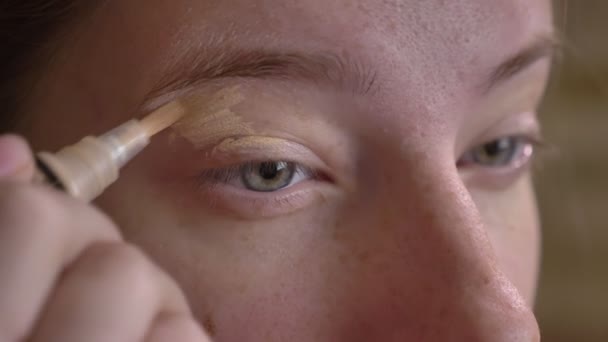 Closeup portret van de jonge Kaukasische make-up artiest een concealer met een borstel toe te passen — Stockvideo