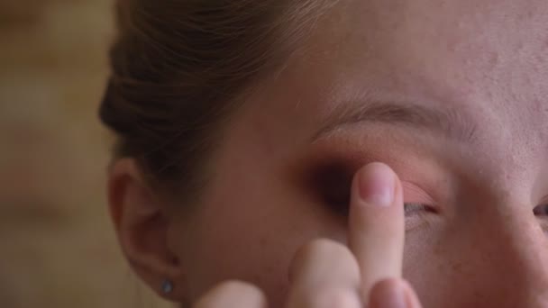 Retrato de close-up de jovem branca artista de maquiagem feminina aplicando iluminador pérola com o dedo — Vídeo de Stock