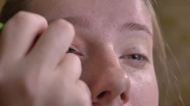 Retrato de primer plano de una joven artista de maquillaje caucásica que aplica delineador de ojos negro en su párpado superior — Vídeos de Stock