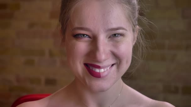 Primer plano retrato de joven impresionante mujer caucásica con maquillaje medio aplicado mirando a la cámara y riendo felizmente — Vídeos de Stock