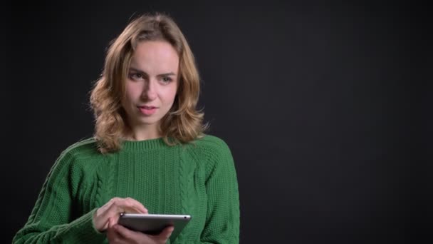 Closeup portrait of adult caucasian female scrolling on the tablet glancing at camera and smiling — Stock Video