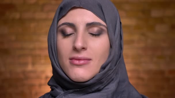 Portret van vrouwelijke handen zetten eyeshadows met borstel voor de moslimvrouw in hijab op bricken muur achtergrond. — Stockvideo