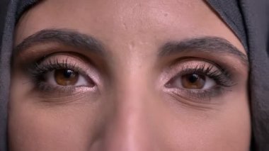 Yakın çekim göz-hijab parlak makyajlı içtenlikle içine kamera siyah arka plan üzerinde gülümseyen güzel Müslüman kadın portresi.