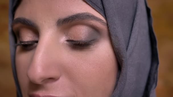 Close-up πορτρέτο της ηρεμίας μεσήλικας Μουσουλμάνα στο χιτζάμπ με φωτεινό μακιγιάζ βλέποντας σε κάμερα σε φόντο τοίχο bricken. — Αρχείο Βίντεο