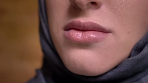 Närbild lip-porträtt i profil av muslimsk kvinna i hijab ler in i kameran på bricken vägg bakgrund. — Stockvideo