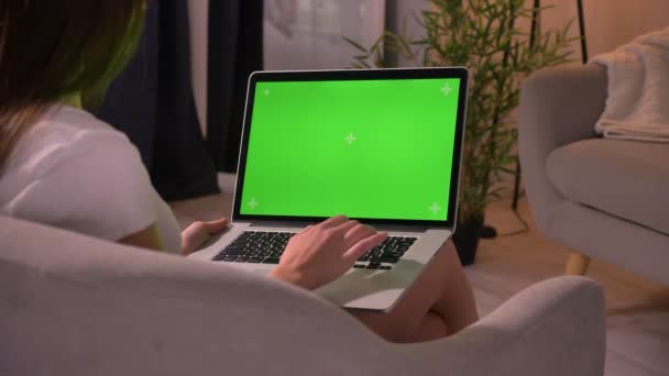 Vértes vissza Nézd használ a laptop-val zöld chroma képernyő, és fordult a kamera mosolygó fiatal kaukázusi nő portréja — Stock videók