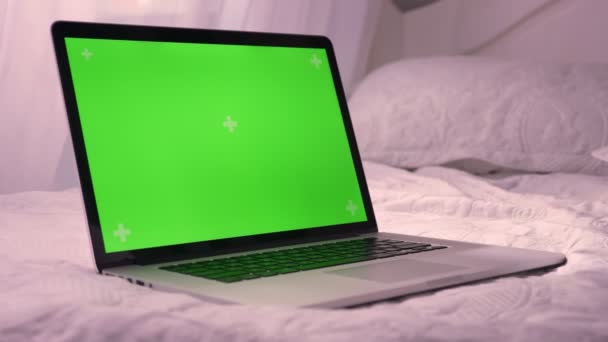 Съемка ноутбука крупным планом с зеленым цветным экраном, лежащим на кровати. Реклама на экране — стоковое видео