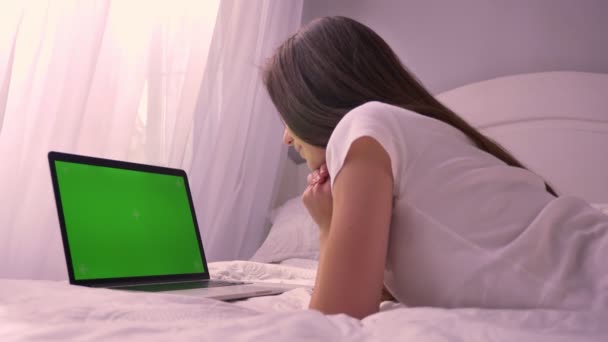 Primer plano vista trasera de la joven mujer caucásica viendo la pantalla verde croma-clave en el portátil en el dormitorio en el interior — Vídeos de Stock