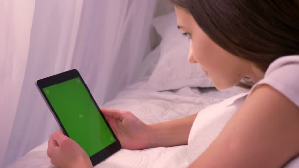 Retrato de close-up de jovem mulher branca atraente reproduzindo um vídeo no tablet com tela verde chroma-key no quarto dentro de casa — Vídeo de Stock