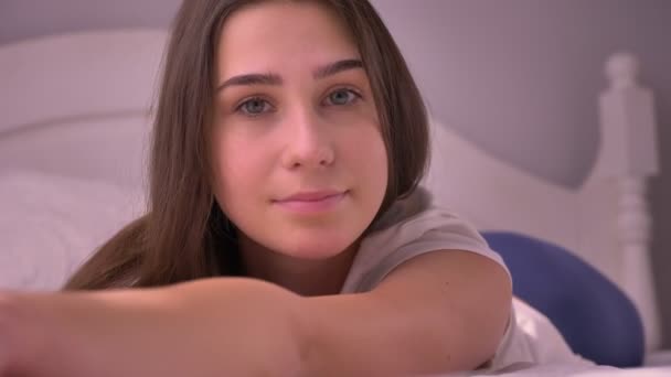 Gros plan portrait de jeune superbe femme caucasienne couchée sur le lit et regardant la caméra souriante — Video