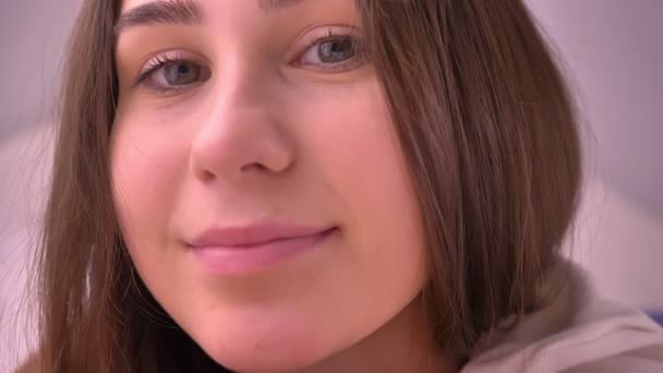 Closeup portrait of young caucasian girl with brown hair looking straight at camera and smiling — Stock Video