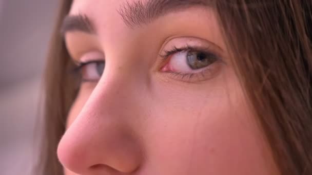 Крупный план портрета молодой кавказки зелеными глазами, поворачивающимися и смотрящими в камеру с улыбкой на лице — стоковое видео