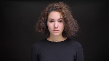 Doğruca kameraya bakarak kıvırcık saçlı genç çekici beyaz kadın portresi portre