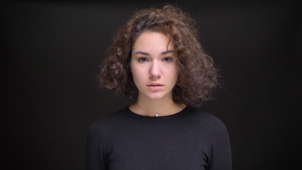 Closeup portrait of young attractive caucasian female with curly hair looking straight at camera — Stock Video
